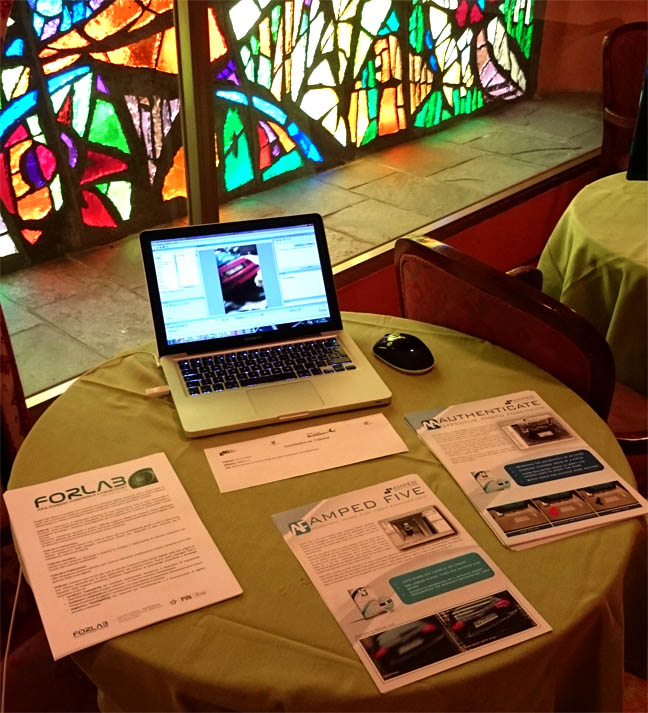 a table with a laptop showing Amped FIVE and brochures laying around