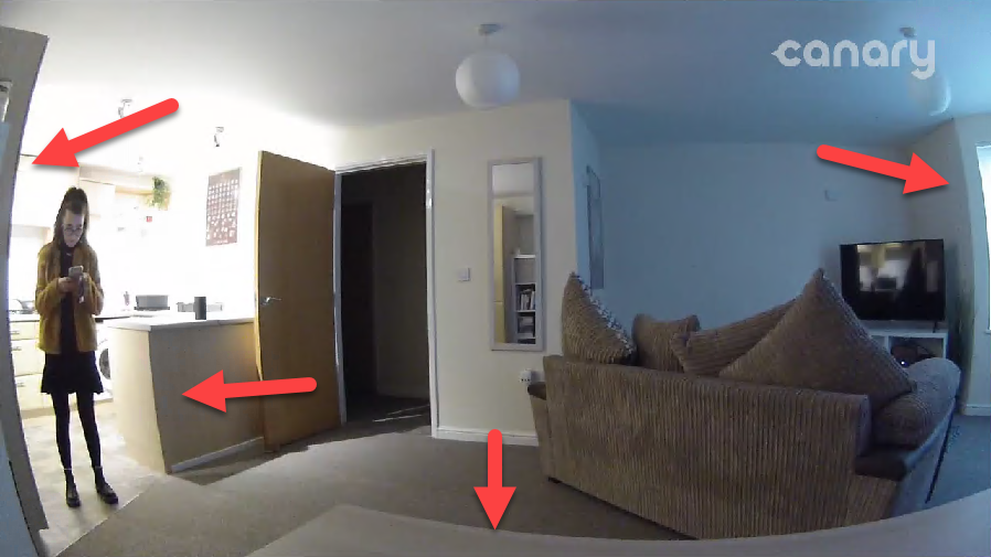 image taken form a cctv camera on a living room with a girl standing beside the counter and walls and lines distorted